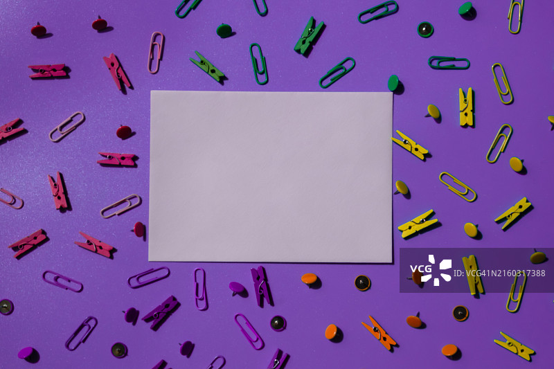 紫色背景上的回形针和紫色纸张俯视图图片素材