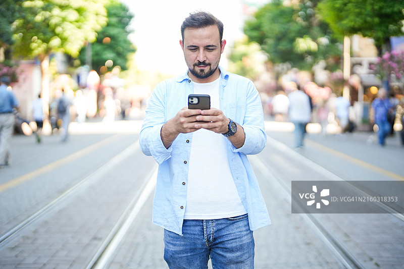 男人在市中心街头看手机并进行银行交易图片素材