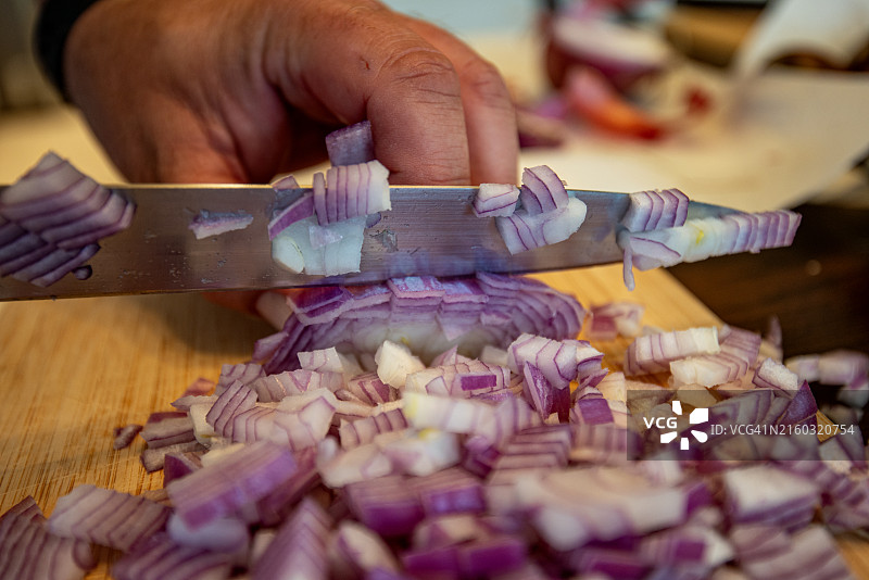 男人在美国加利福尼亚州圣地亚哥的砧板上切食物的局部照片图片素材