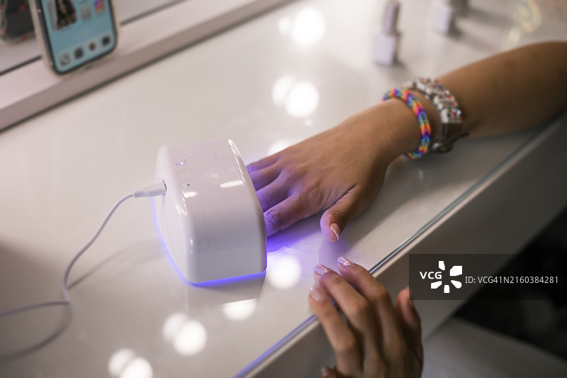 美甲时在紫外线灯下烘干指甲图片素材