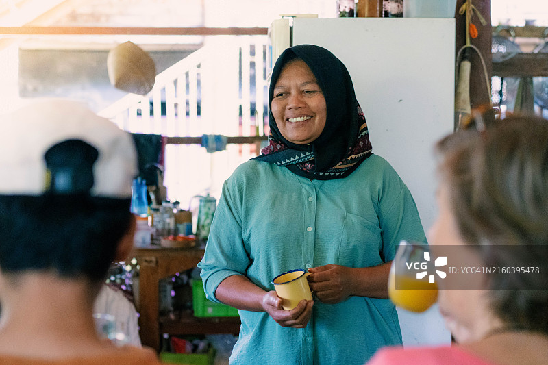 穆斯林家庭旅馆女主人用珐琅玻璃杯为客人端饮料图片素材