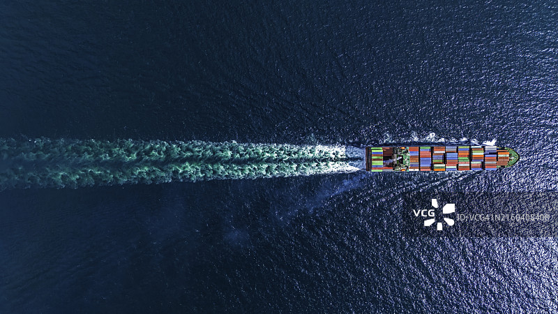 全速航行的集装箱船在蓝色海面上划出美丽的波浪图片素材