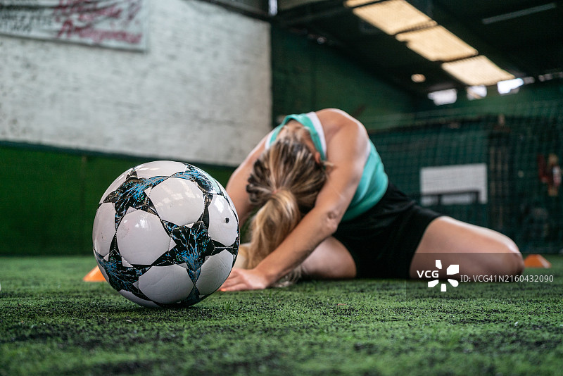 足球场上足球与正在拉伸的女子特写图片素材