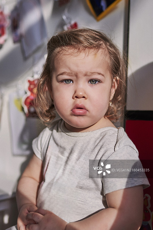 一个两岁女孩皱着眉头嘟着嘴看着镜头图片素材