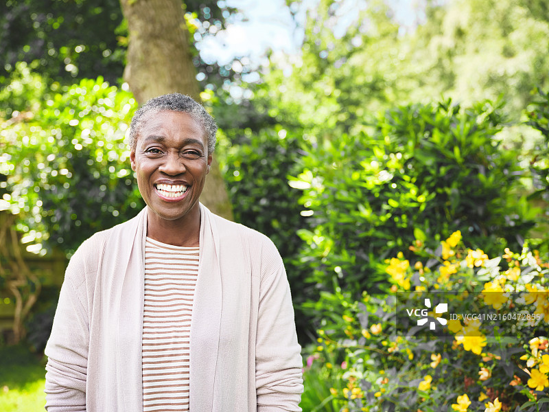 一位自信的中年妇女在花园里高兴地看着镜头，一位老年妇女在户外度过轻松的一天图片素材