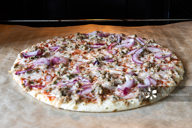 烤箱烤盘上做好的金枪鱼热披萨图片素材