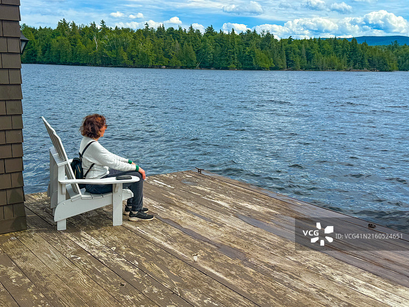 坐在露台上，眺望蓝山湖清澈湖水的女人图片素材