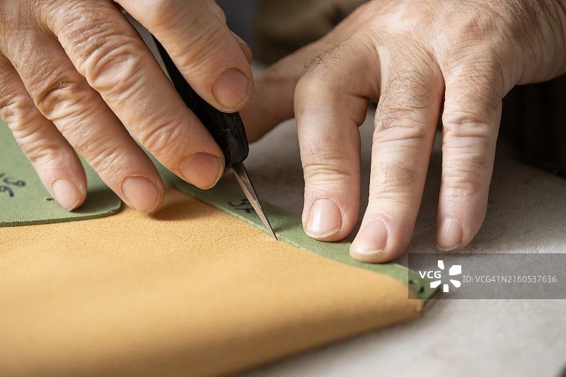 经验丰富的工匠在鞋厂切割皮革图片素材