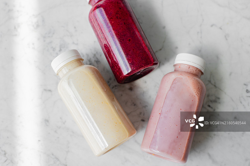 大理石桌上生态塑料瓶装浆果水果冰沙饮品图片素材