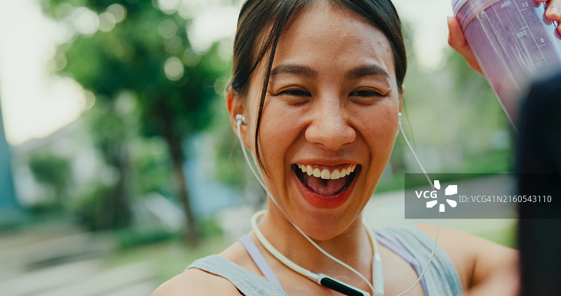 亚洲女运动员在公园与健身教练视频通话特写图片素材
