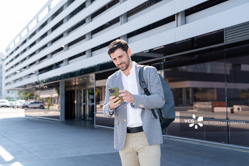 商务人士在办公楼附近使用智能手机App图片素材