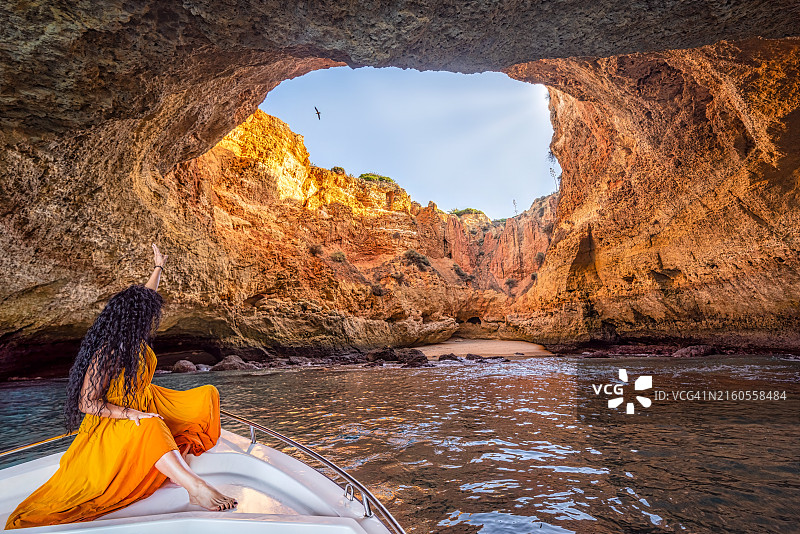 葡萄牙阿尔加维三城堡海滩洞穴中穿黄色连衣裙的女子图片素材