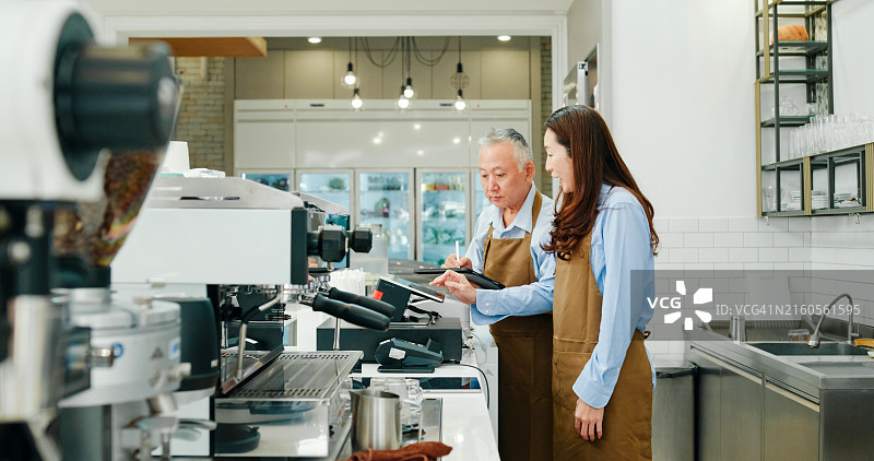 年长的亚洲创业者夫妇在咖啡馆使用平板电脑管理订单，小企业主图片素材