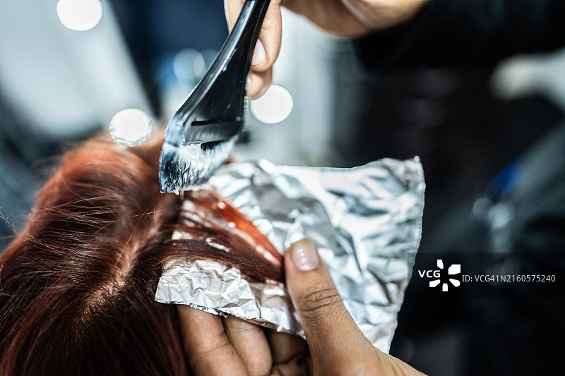 理发师在美发沙龙为顾客染发特写图片素材