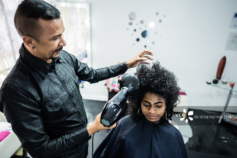 美发师在美发沙龙为顾客吹头发图片素材