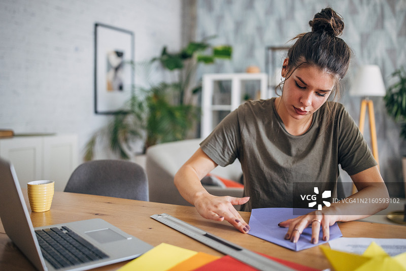 女人在桌边仔细地折叠紫色纸张图片素材