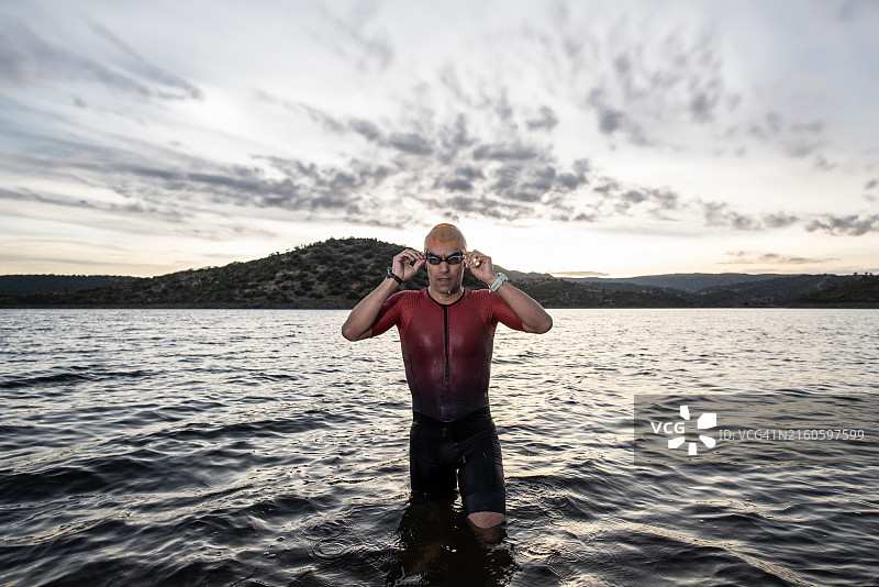 铁人三项运动员在沼泽中调整泳镜进行训练图片素材