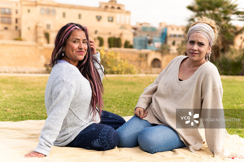 两位女人在冥想后在户外毯子上放松图片素材