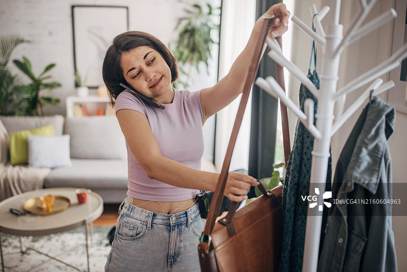 女人把包挂在家里的衣架上图片素材
