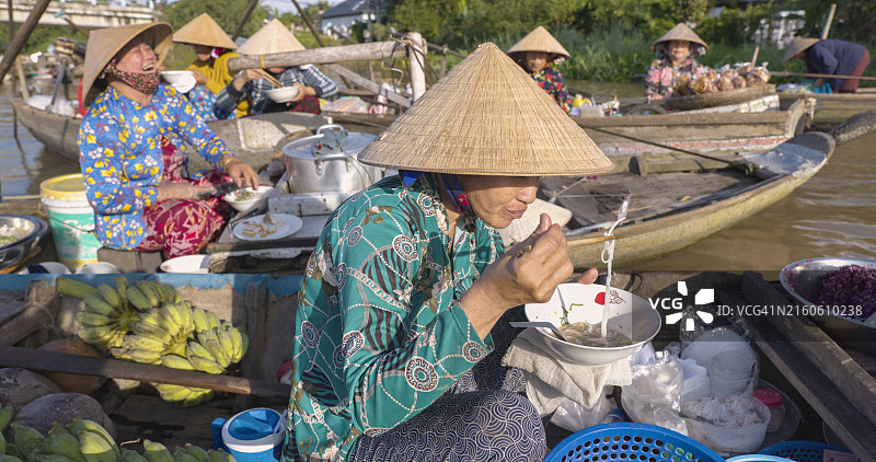 越南湄公河三角洲水上市场，越南妇女在吃著名的米粉汤图片素材