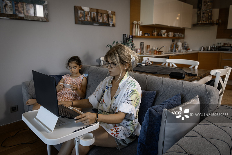 女孩在玩手机，妈妈在工作图片素材