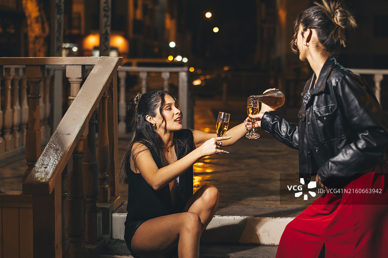 朋友们在参加派对前在街上倒酒图片素材