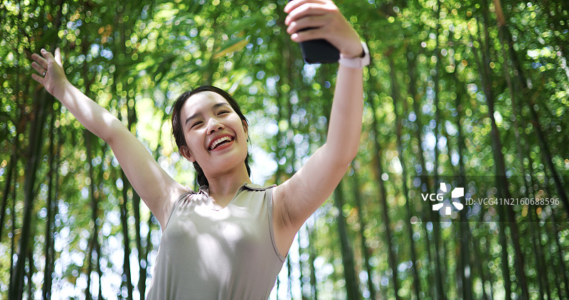 年轻女性在竹林中用手机自拍图片素材