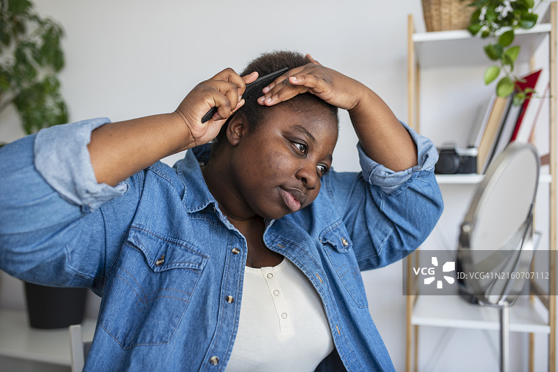 年轻大码女性在家在镜子前梳头图片素材