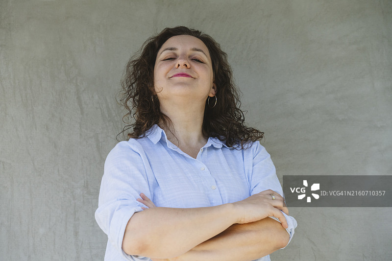 闭着眼睛靠在灰色墙上的疲惫女人图片素材