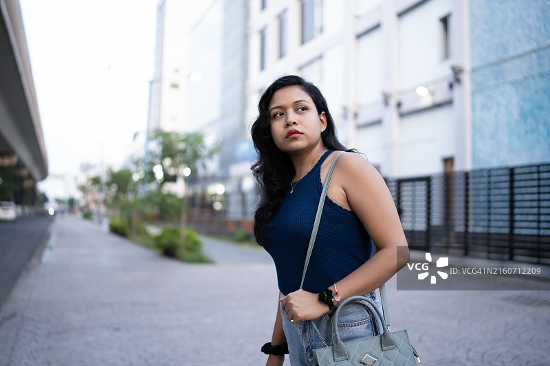 身穿蓝色上衣的年轻女子正在叫出租车图片素材