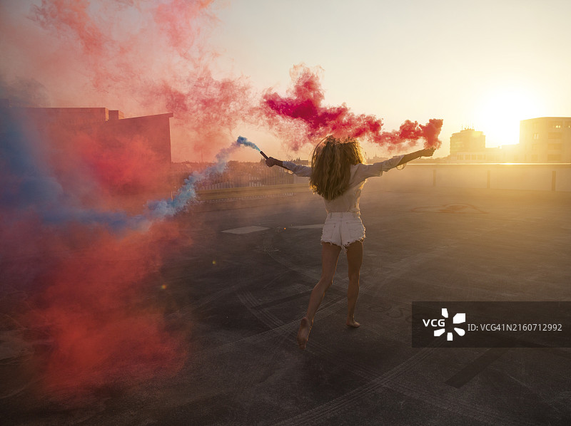 女子手持烟雾弹欣赏日落图片素材