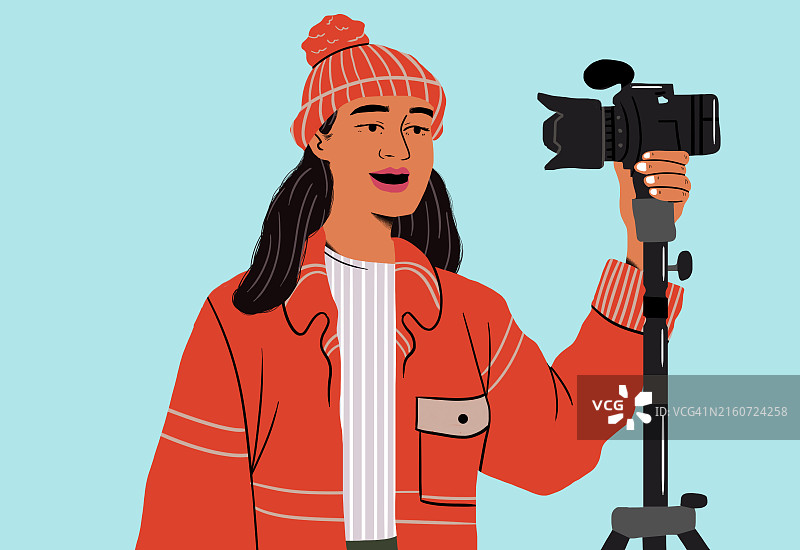 在蓝色背景下拿着三脚架上的相机的微笑女人图片素材
