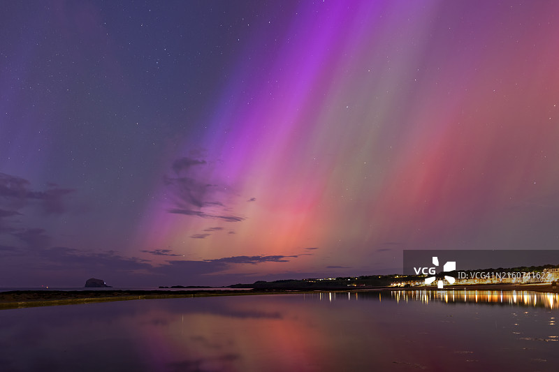 英国苏格兰北贝里克，夜晚沿海城镇上空的北极光图片素材