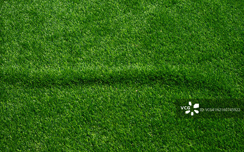 未完成的褶皱绿色人造草皮：用于覆盖运动场或花园的人造草皮图片素材