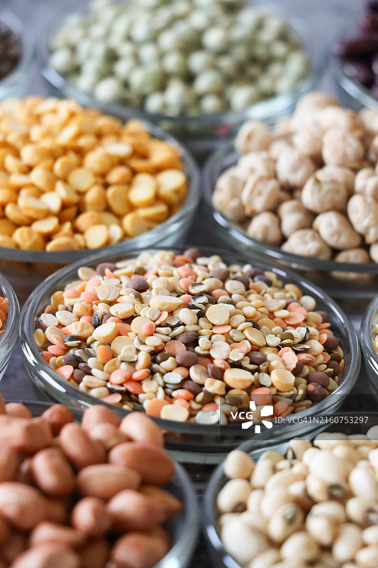 装满豆类、坚果和种子的玻璃碗特写，包括混合去皮小扁豆、红皮花生、干黑眼豆、去皮黄扁豆、干鹰嘴豆、干青豆图片素材