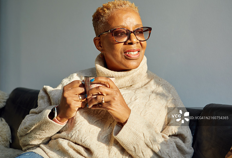 笑容满面的年长妇女在沙发上放松图片素材