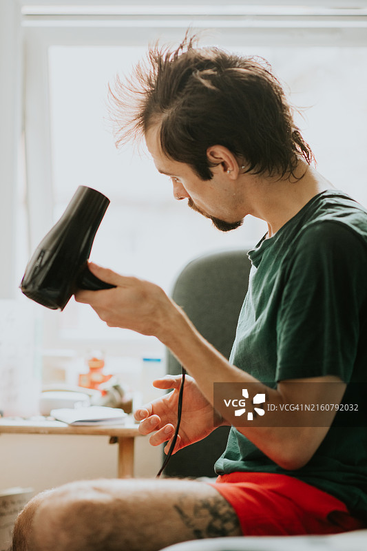 男人用吹风机吹干头发图片素材