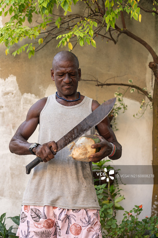 男子在户外用大砍刀切椰子图片素材