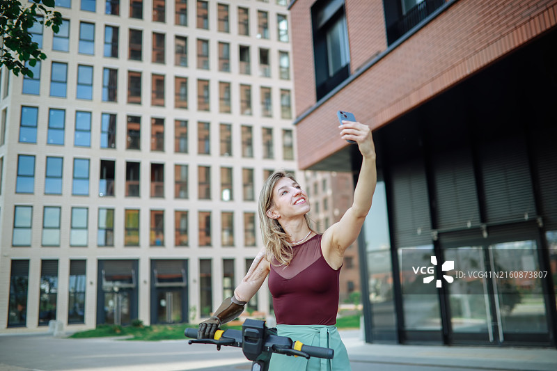 城市便利设施和环保交通：使用租赁滑板车和智能手机的假肢女性图片素材