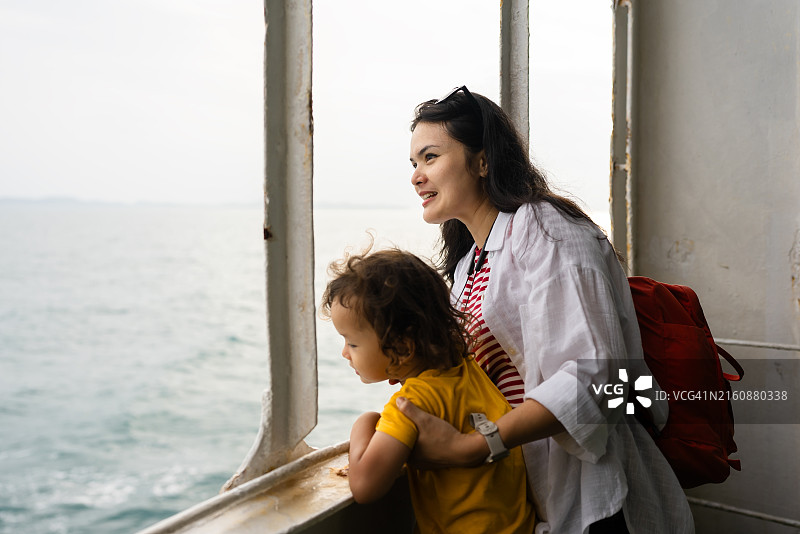 亚洲母亲和儿子在游轮上眺望大海图片素材