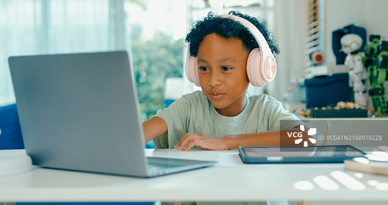 非裔美国少年在家使用笔记本电脑和数位板积极参与线上课程图片素材