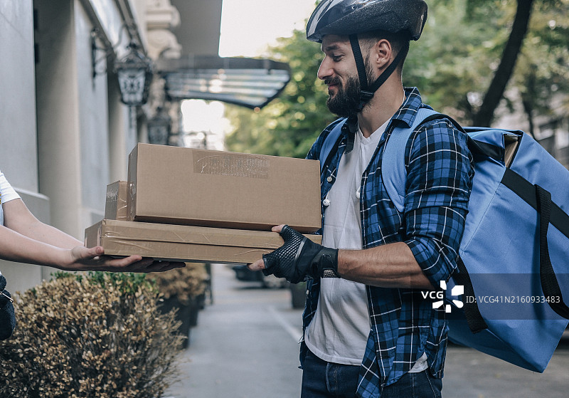 快递员在城市街道上给女士送包裹图片素材