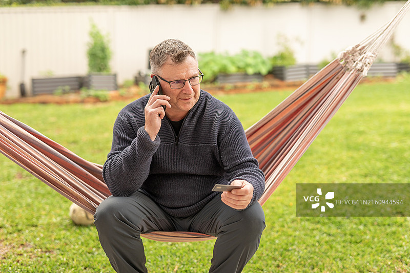 中年男子在后院使用手机和信用卡图片素材