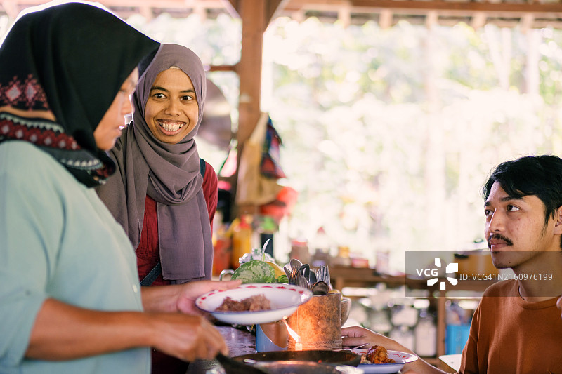 准备饭菜的中年穆斯林妇女与等待的客人图片素材