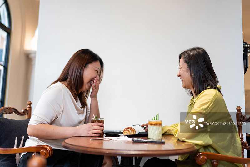 两位中国女性朋友在咖啡店愉快地聊天图片素材