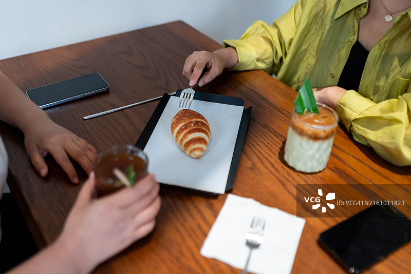 两位中国女性在咖啡馆约会，桌上有咖啡和面包图片素材