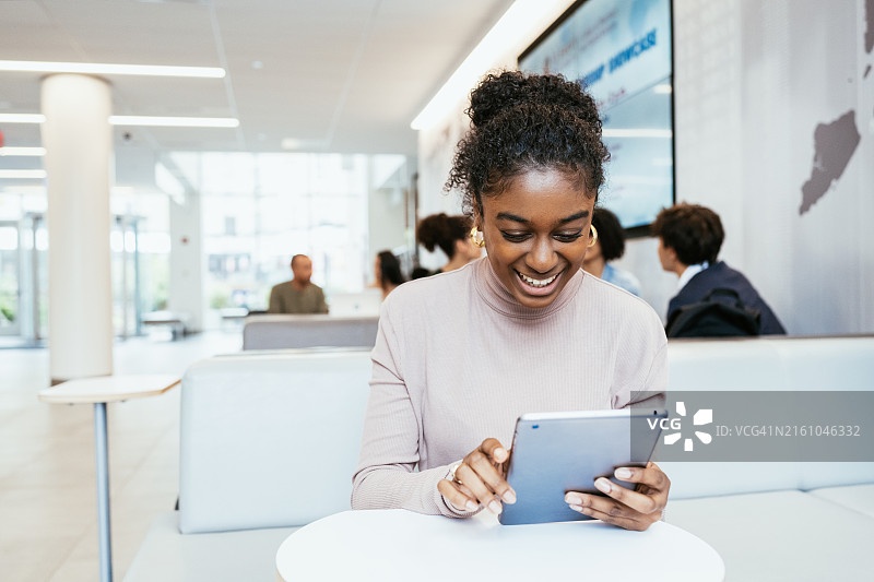 微笑的印度妇女在现代室内使用数字平板电脑，例如在联合办公空间或办公室图片素材