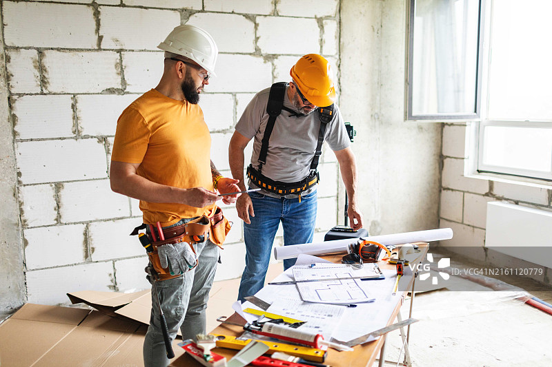 两名建筑工人在施工现场使用平板电脑分析蓝图图片素材