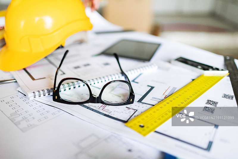 建筑工地桌上的工作工具特写：蓝图、眼镜、图纸、尺子和其他家居改进工具图片素材