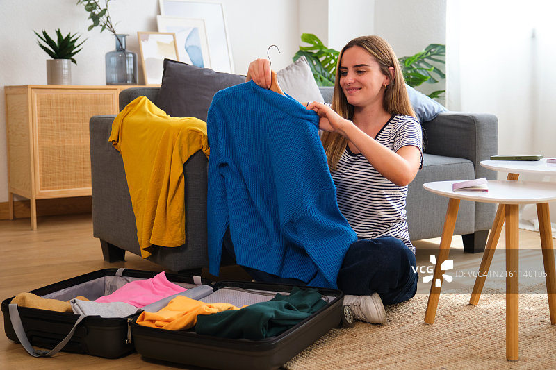 年轻女人在家整理行李箱挑选衣服图片素材